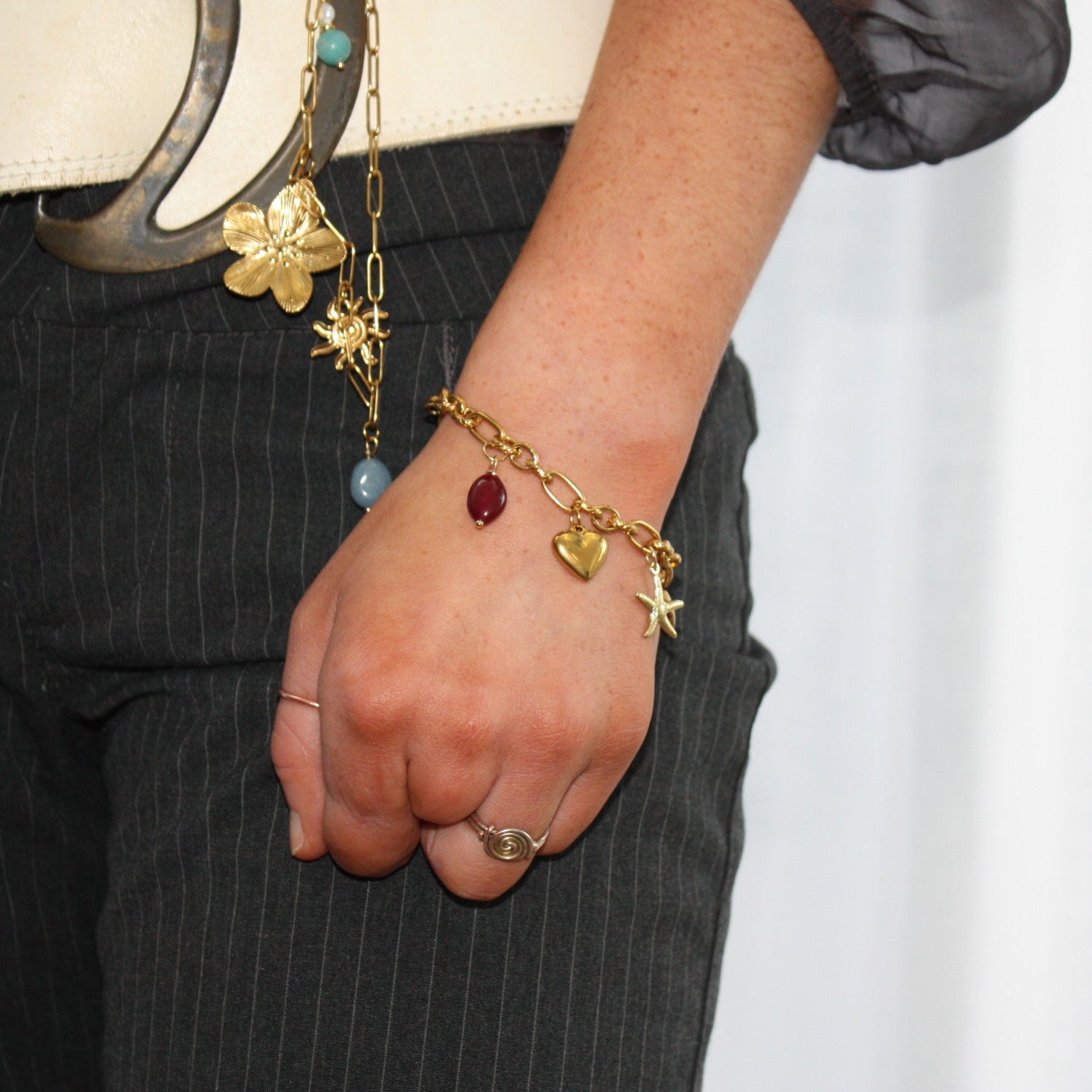 A stylish Custom Charm Bracelet worn on a hand, showcasing charming elements like hearts and stars, perfect for adding a personal flair to any outfit.