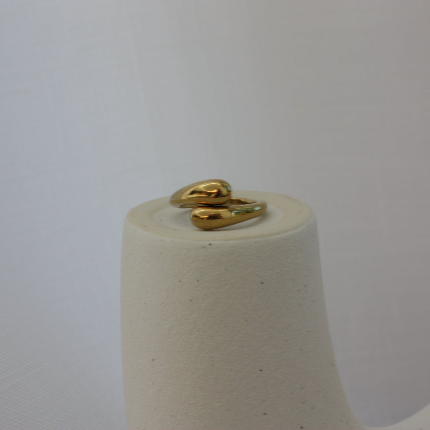 Beautiful adjustable gold ring by ÈRE displayed atop a decorative stand, highlighting its versatile design and luxurious 18K gold plating.