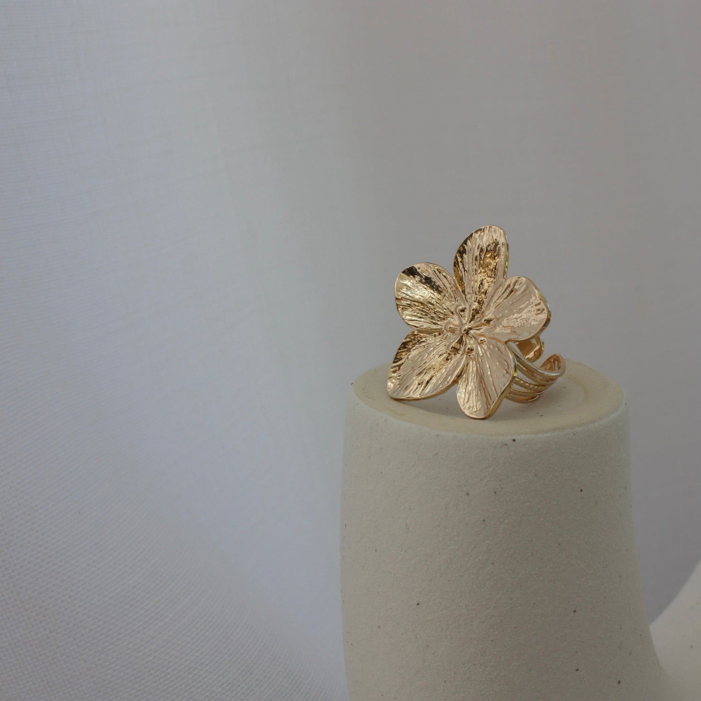 The Fleur Ring displayed artistically on a minimalist pedestal, illustrating its floral design in a stunning presentation by ÈRE, highlighting it as a flower statement ring.