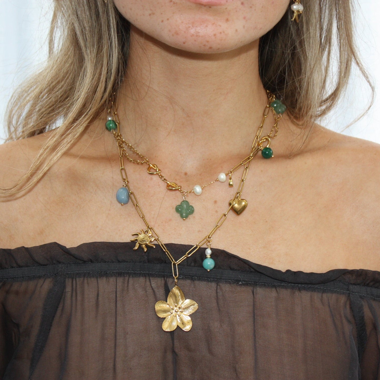 Model wearing the Asymmetric Charm Necklace layered with various charms, highlighting its unique asymmetric design with gold accents and natural stones.