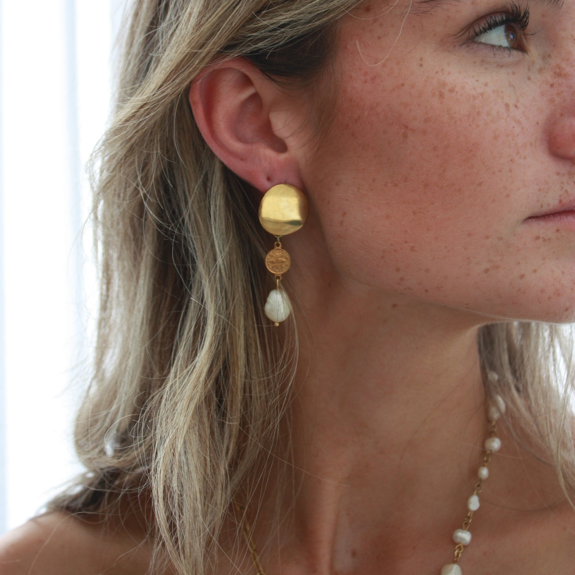 Model wearing stylish pearl earrings with gold accents, showcasing the elegant design of 18k Gold PVD plated stainless steel and unique freshwater pearls.