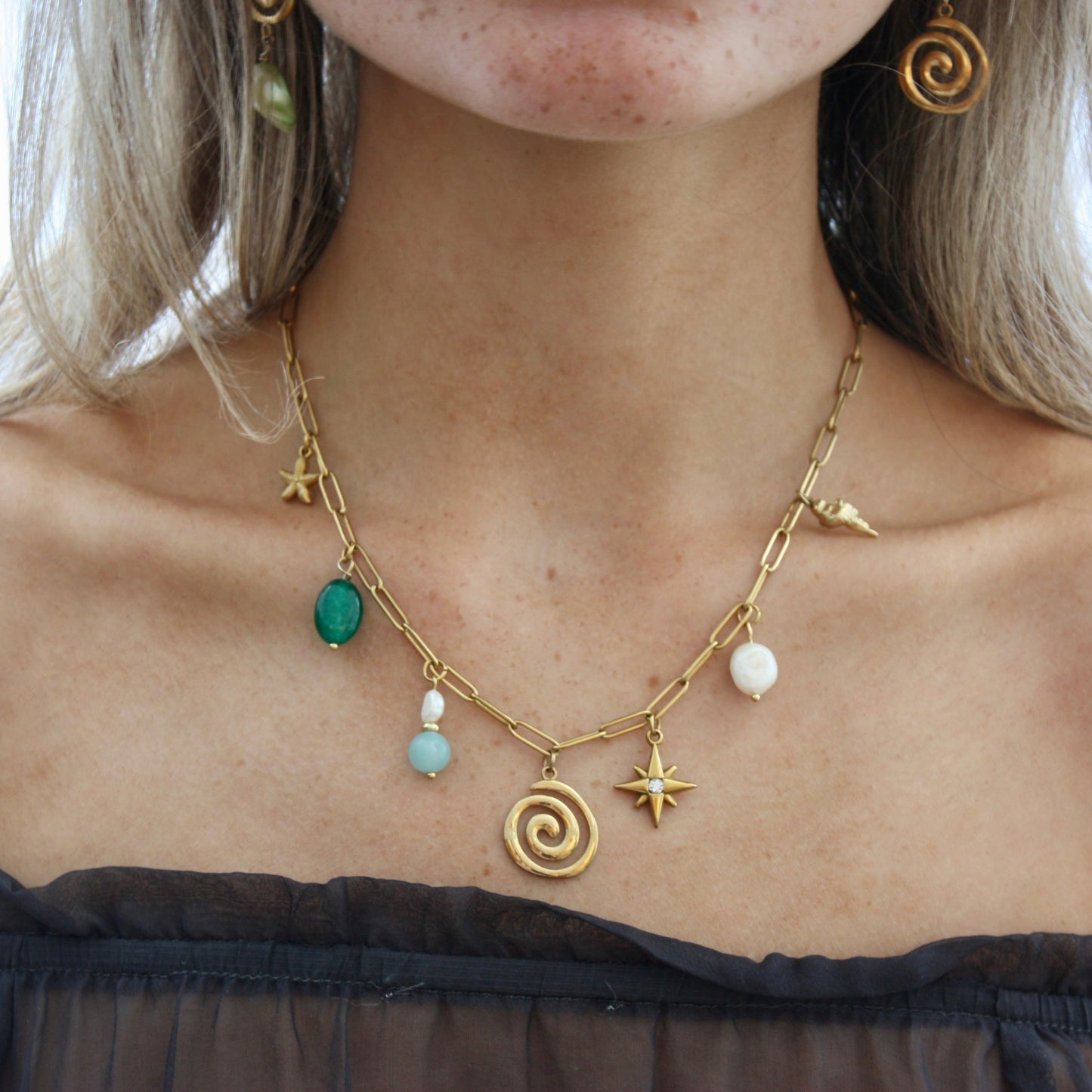 Stylish woman showcasing a personalised Custom Charm Necklace adorned with multiple charms including star and pearl accents.