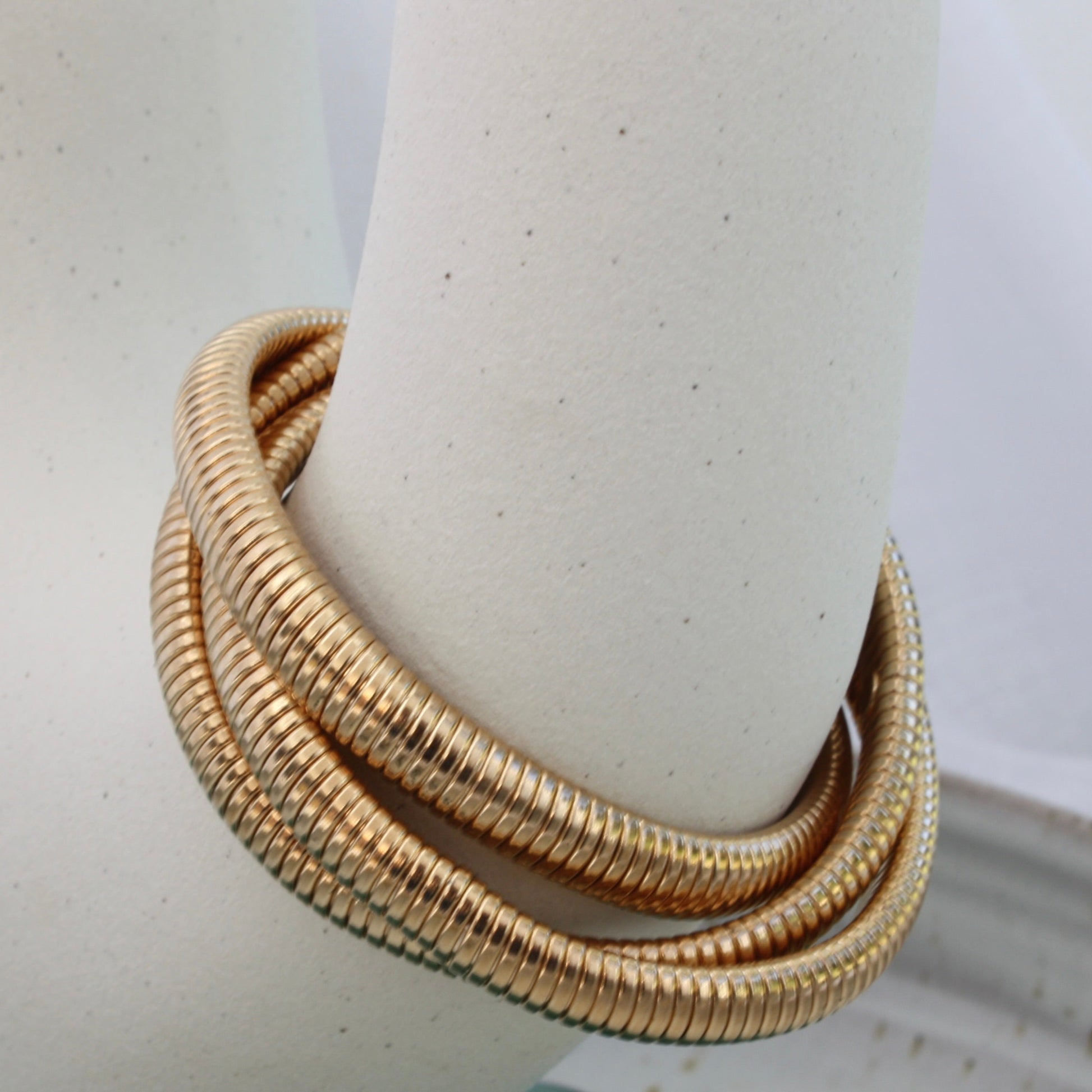 Rowe Bangle by ÈRE elegantly resting on a display piece, the modern gold bangle showcases a chic and sophisticated look.