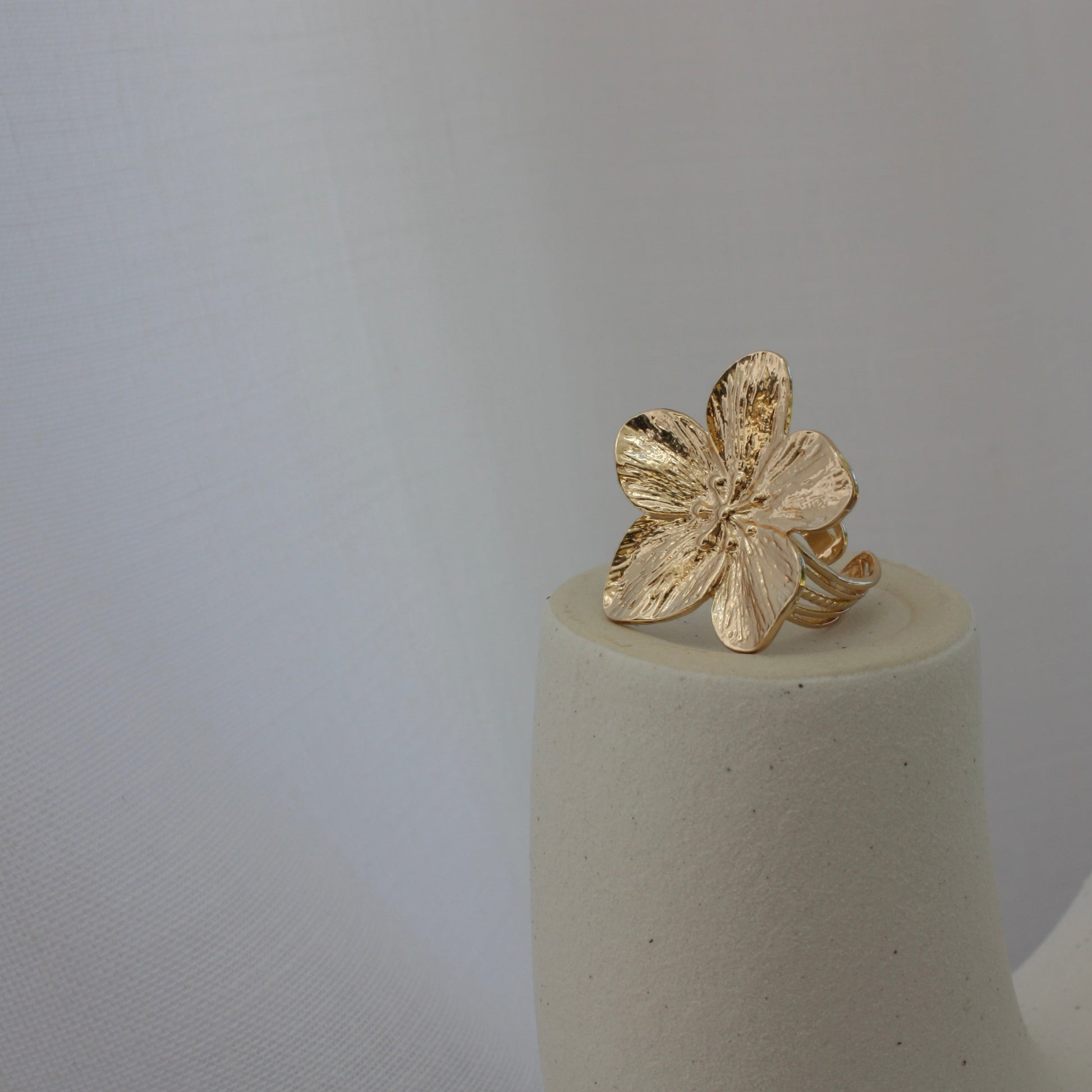 The Fleur Ring displayed artistically on a minimalist pedestal, illustrating its floral design in a stunning presentation by ÈRE, highlighting it as a flower statement ring.