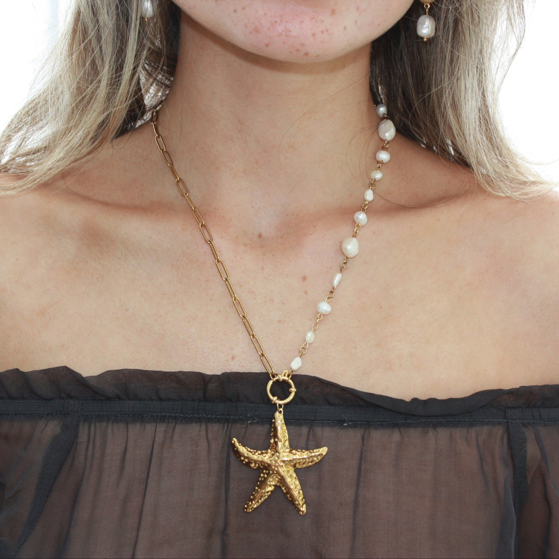 Model wearing the Milos Pearl Charm Necklace with a starfish charm, showcasing its unique design and asymmetrical style.