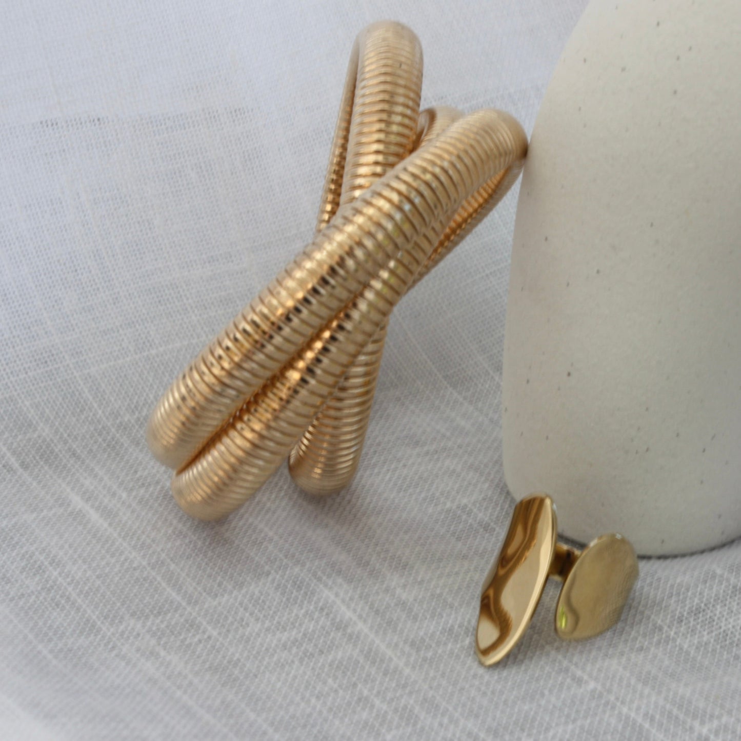 Rowe Bangle by ÈRE artistically placed next to fashion items, emphasising the trendy appeal of the gold bangle in outfit styling.