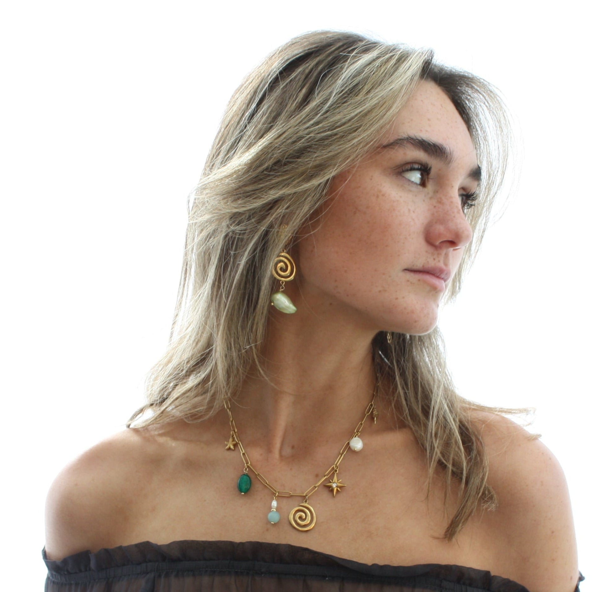 Model wearing stylish spiral pearl earrings, complemented by a matching necklace, highlighting the chic asymmetric design with baroque freshwater pearls and a golden spiral detail.