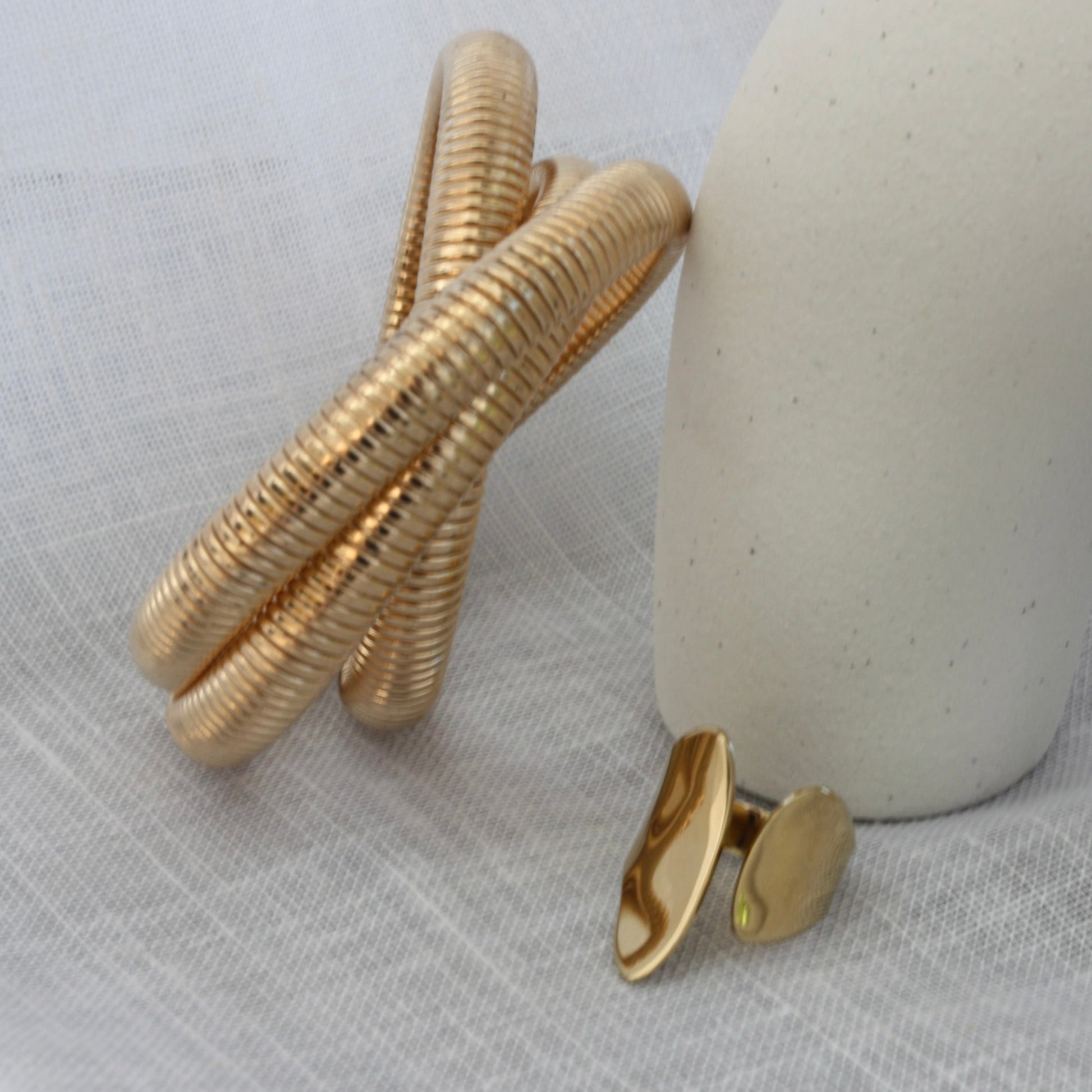 A visually stunning presentation of the Sloane Ring by ÈRE, alongside a gold bracelet. This adjustable gold ring embodies contemporary elegance with its unique design.