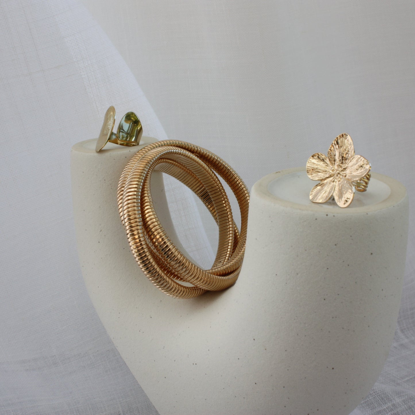 The Sloane Ring by ÈRE pictured with other jewellery pieces, featuring a minimalist aesthetic. This adjustable gold ring is a must-have for any stylish collection.