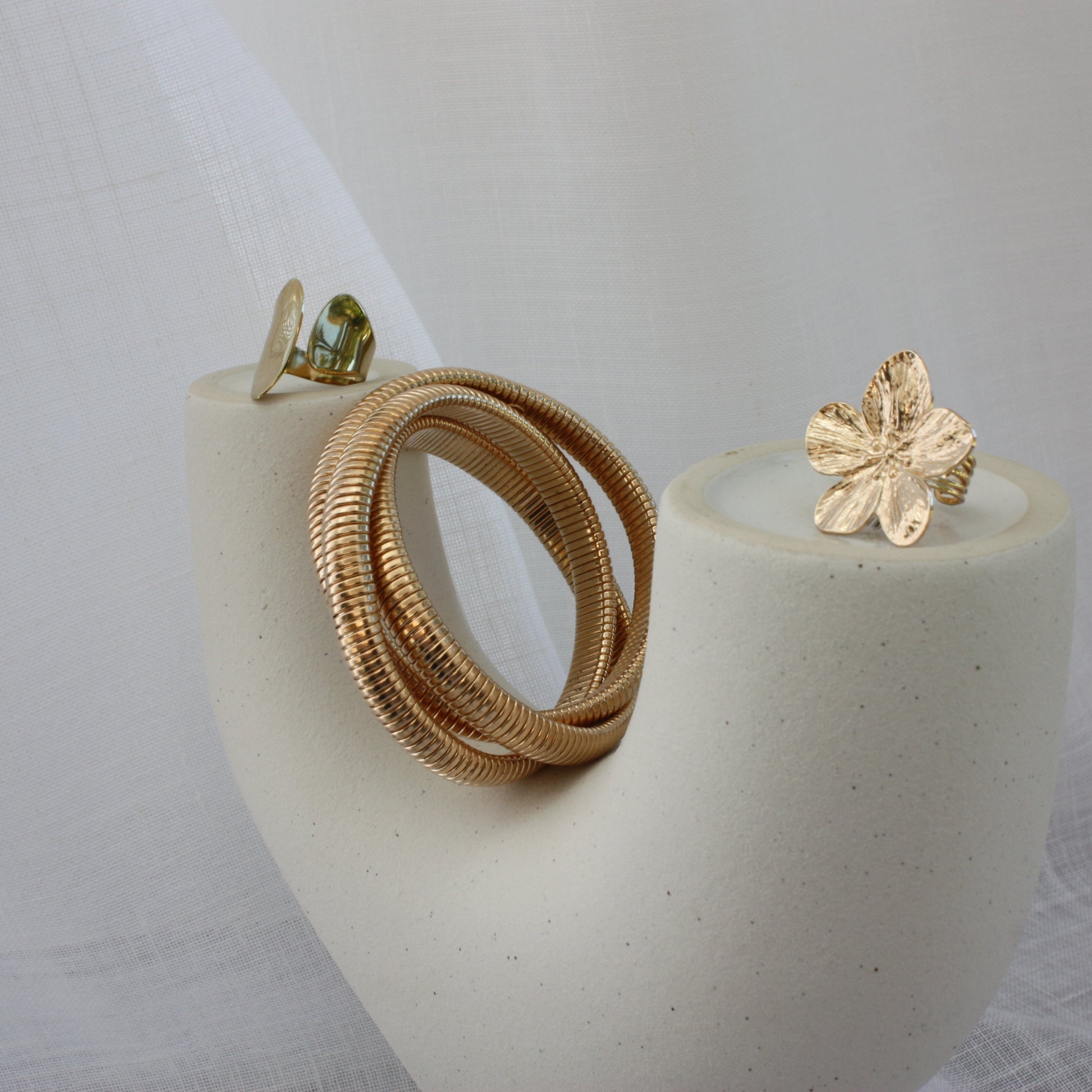 The Sloane Ring by ÈRE pictured with other jewellery pieces, featuring a minimalist aesthetic. This adjustable gold ring is a must-have for any stylish collection.